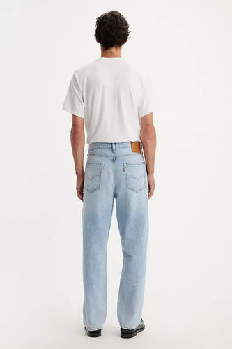 Lichtblauwe rechte jeans van Levi's, gezien van achteren met een wit T-shirt en zwarte schoenen.
