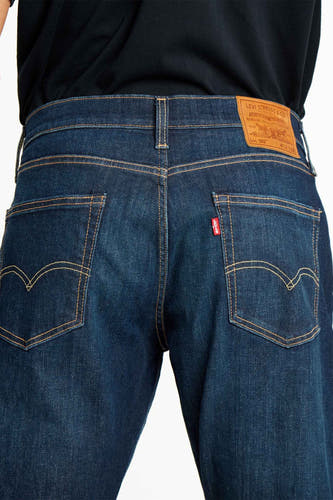 Donkerblauwe tapered jeans van Levi's, met kenmerkende stiksels op de achterzakken en een leren patch op de tailleband.
