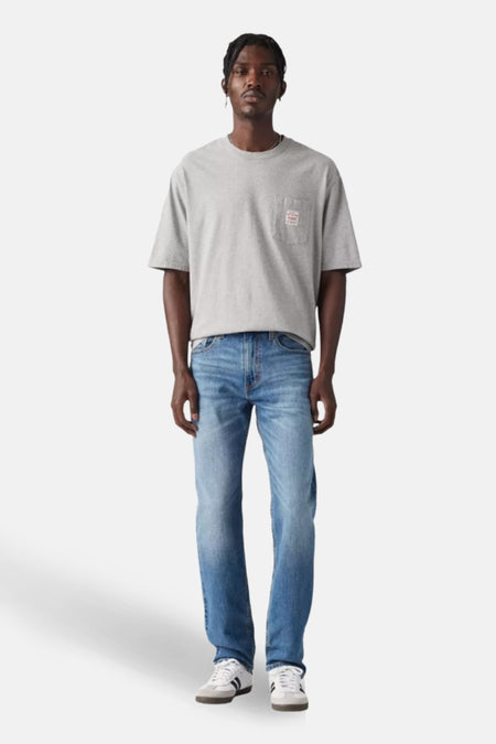 Taps toelopende jeans van middenblauw denim van Levi's, gedragen met een grijs T-shirt en witte sneakers.
