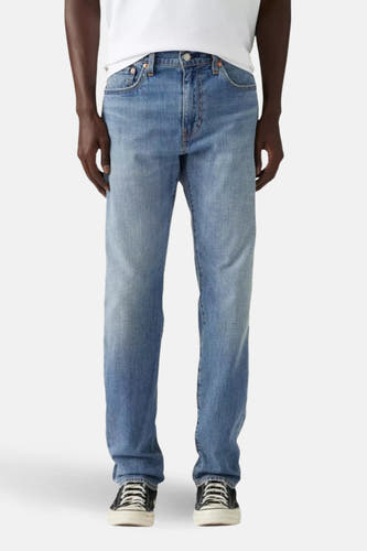Lichtblauwe tapered jeans van Levi's, gedragen met een wit t-shirt en zwart-witte sneakers.
