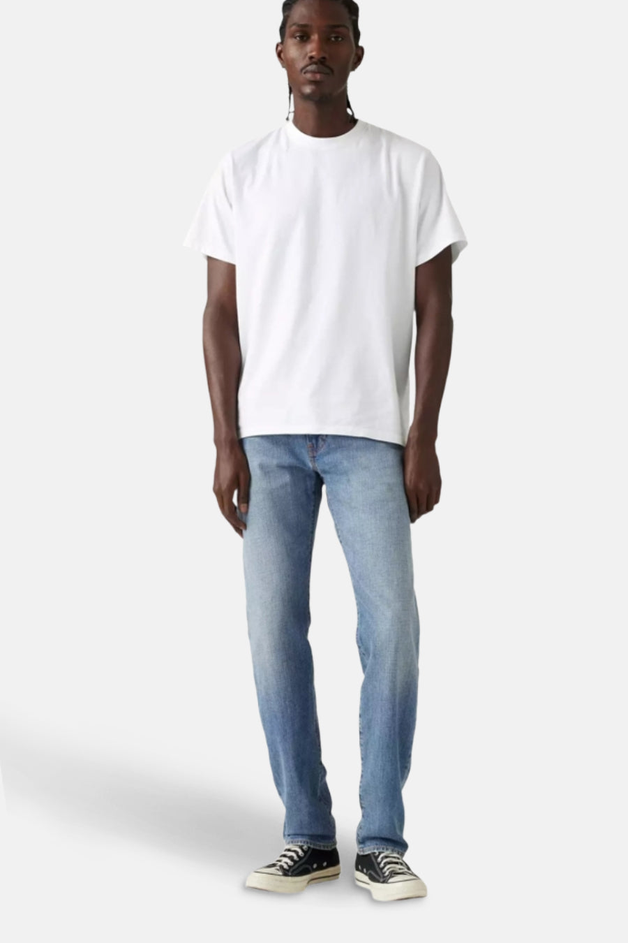 Lichtblauwe tapered jeans van Levi's®, gedragen met een wit T-shirt en zwarte sneakers.
