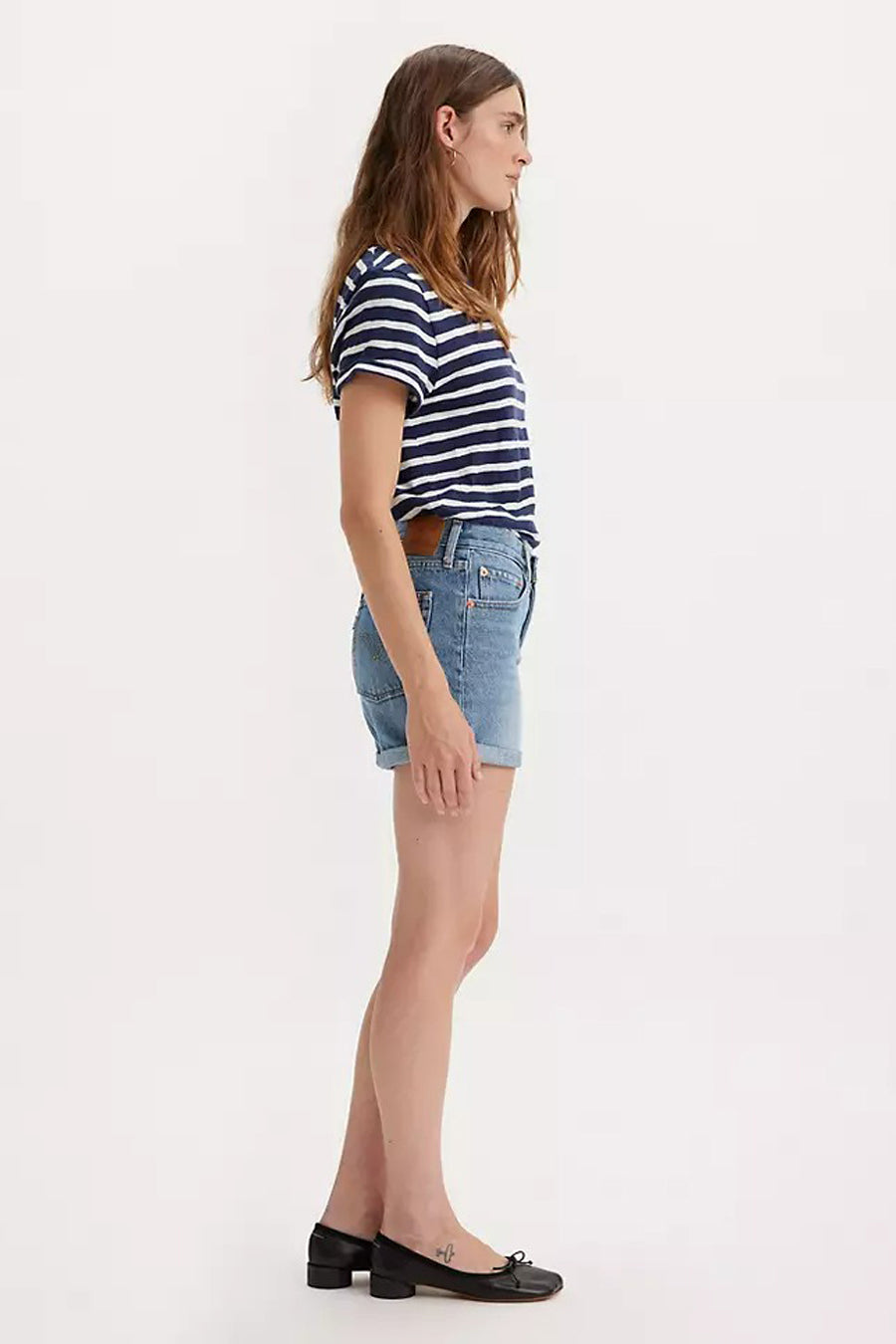 Denim short van Levi's, met opgerolde pijpen, gecombineerd met een gestreepte top en zwarte schoenen, in zijaanzicht.
