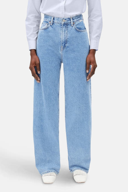 Lichtblauwe wijde jeans van ARMEDANGELS, gedragen met een wit overhemd en witte espadrilles.