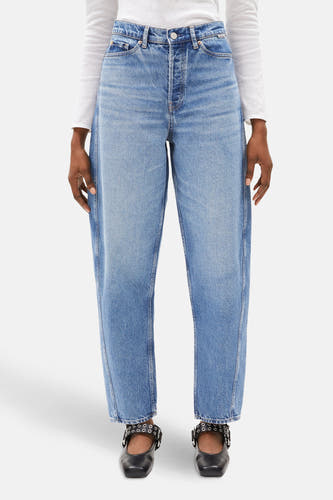 Jean en denim bleu marine d'ARMEDANGELS, avec des poches arrière et une étiquette en cuir, porté avec un t-shirt en mesh blanc.