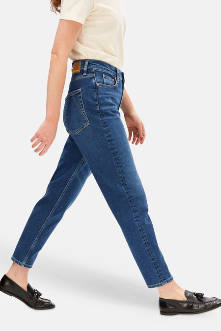 Donkerblauwe mom jeans van Armed Angels, zijwaarts lopend model, met crèmekleurig shirt en zwarte loafers