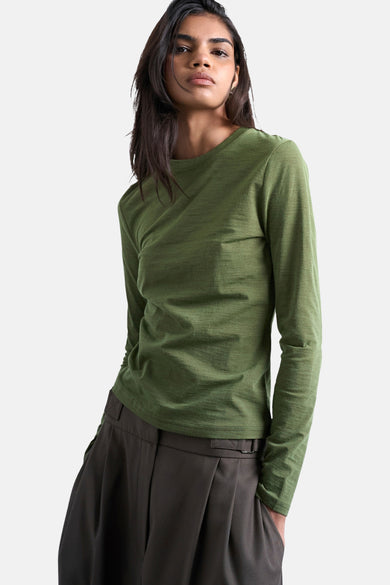 Groen T-shirt met lange mouwen van TOPSHOP, gedragen met een bruine broek met wijde pijpen.