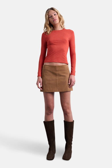 T-shirt à manches longues orange de TOPSHOP, porté avec une mini-jupe en daim marron et des bottes marron montantes jusqu'aux genoux.