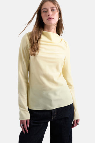 T-shirt jaune à manches longues de TOPSHOP, porté avec des jeans foncés et des sandales avec des lanières.