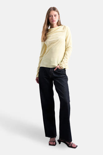 Gele T-shirt met lange mouwen van TOPSHOP, gedragen met donkere jeans en hakken met bandjes.
