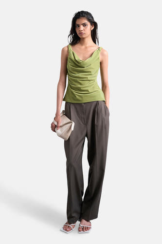 Groene mouwloze top van TOPSHOP, met gedrapeerde halslijn, gecombineerd met een grijze pantalon en witte sandalen.
