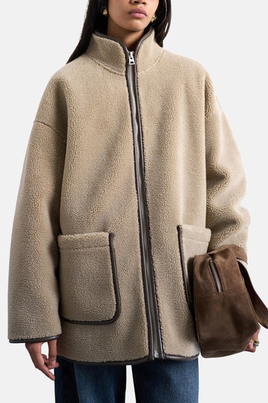 Beige jas van TOPSHOP, met ritssluiting en zakken, en een bruine suède tas.
