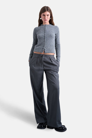 Grijze cardigan van TOPSHOP, met lange mouwen en een knoopsluiting, gedragen met een grijze broek en zwarte schoenen.
