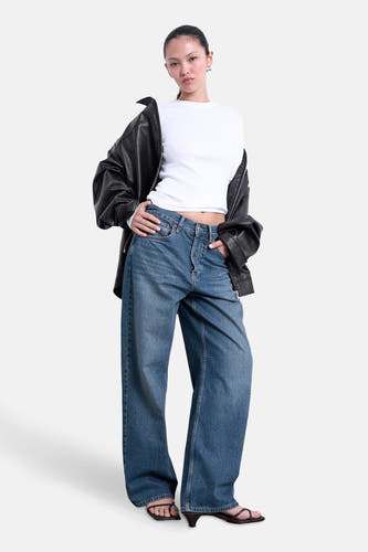 Wit T-shirt met lange mouwen van TOPSHOP, gedragen onder een zwarte leren jas en wijde jeans.