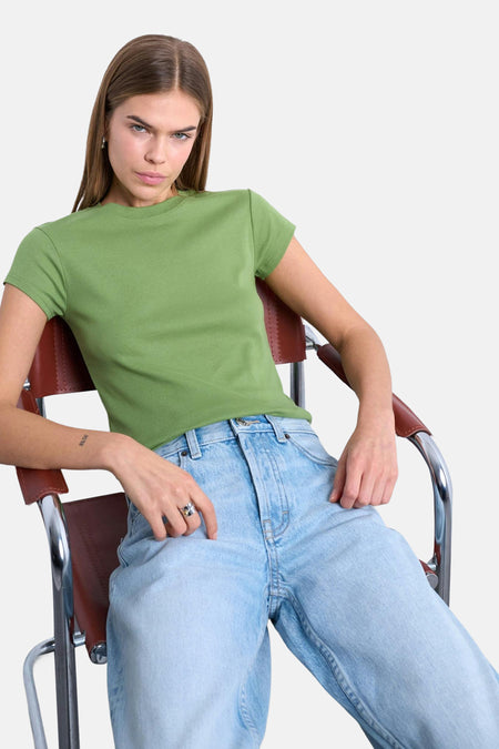 Groen T-shirt met korte mouwen van TOPSHOP, gedragen met een blauwe jeans in een nonchalante zithouding.
