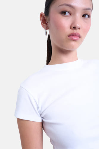Wit T-shirt met korte mouwen van TOPSHOP, gedragen door een model met zilveren oorbellen.