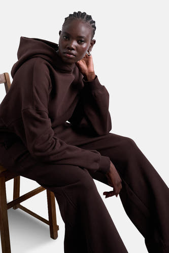 Bruine sweater met kap van TOPSHOP, zittend model met zilveren oorbellen en een bijpassende broek.
