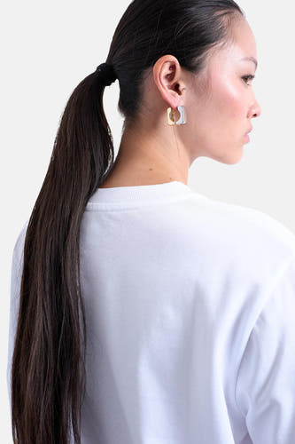 Wit T-shirt met korte mouwen van TOPSHOP, met een vrouw met donker haar in een paardenstaart en vierkante oorbellen.
