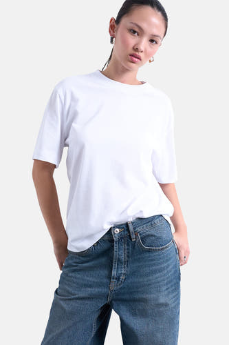 Wit T-shirt met korte mouwen van TOPSHOP, gedragen met jeans en gouden oorbellen.