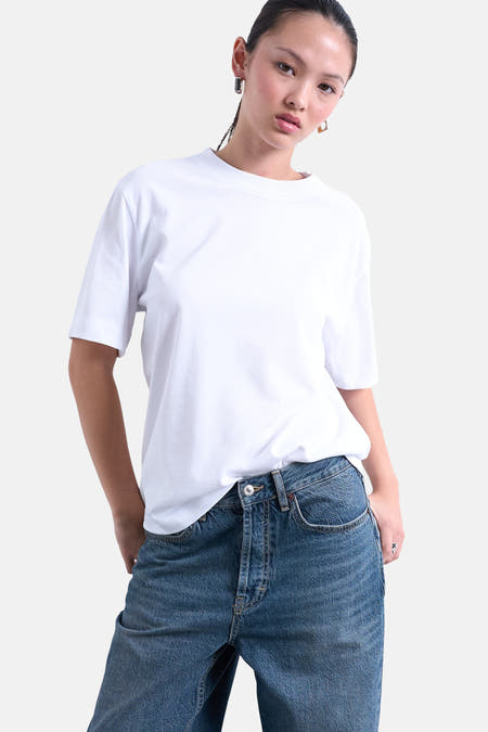 Wit T-shirt met korte mouwen van TOPSHOP, gedragen met jeans en gouden oorbellen.