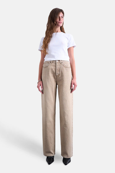 Beige rechte jeans van TOPSHOP, gecombineerd met een wit T-shirt en een zilveren armband.
