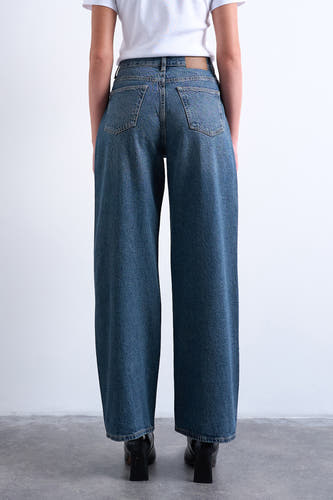 Jeans straight van middenblauw denim van TOPSHOP, gezien van achteren met wijde pijpen en zwarte blokhaklaarzen.
