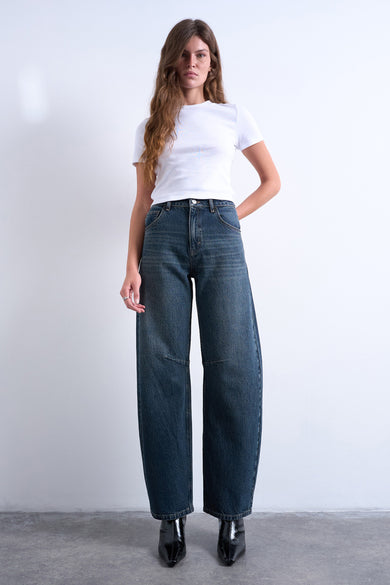 Jeans special fit van blauwzwart denim van TOPSHOP, met wijde pijpen en gedragen met een wit T-shirt en zwarte enkellaarsjes.
