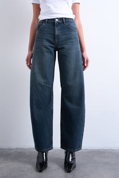 Jeans special fit in blauwzwarte denim van TOPSHOP, met wijde pijpen, gecombineerd met een wit T-shirt en zwarte laarzen.
