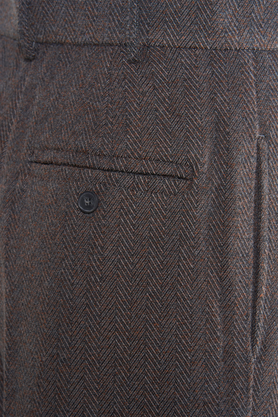 Bruine wollen broek met visgraatmotief en knoopzak.
