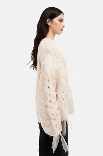 Ecru ronde hals trui van TOPSHOP, met kabelpatroon en decoratieve organza stroken, in zijaanzicht, gecombineerd met een zwarte jeans en gouden oorbellen.
