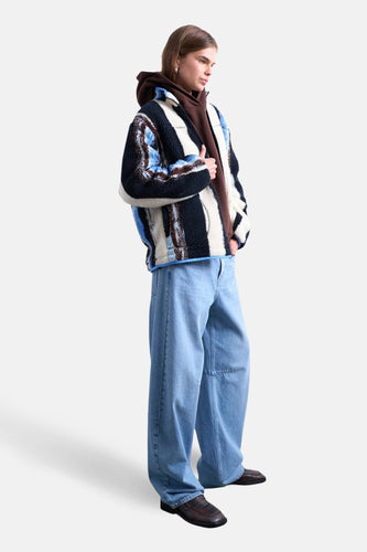 Multikleurige korte jas van TOPSHOP, met streepjespatroon en gedragen over een bruine hoodie en wijde jeans.