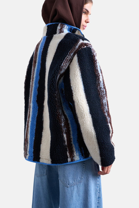 Persoon met gestreepte fleecejas en blauwe jeans.