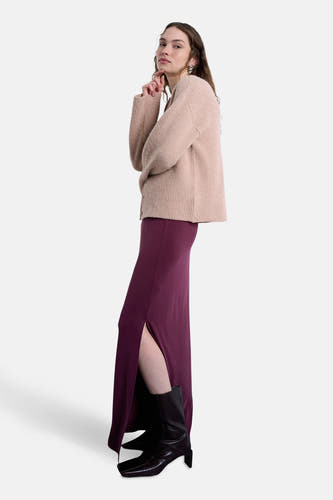 Lange rode rok van TOPSHOP, met een split aan de zijkant, gecombineerd met zwarte laarzen en een beige vest.
