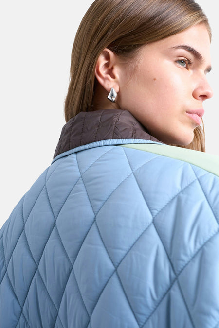 Bruine korte jas van TOPSHOP, met een lichtblauwe diamant gewatteerd patroon en een mintgroene bies.
