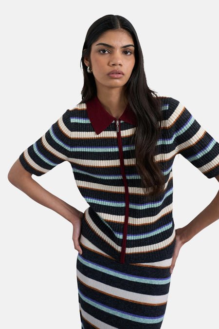 Een vrouw met gestreept shirt en rok, met de handen in haar zij.