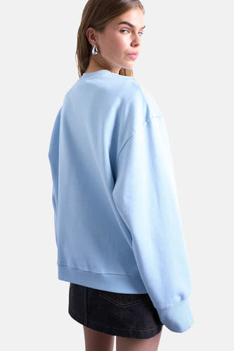Blauwe sweater van TOPSHOP, met lange mouwen en ronde hals, gedragen met een donkerblauwe rok.
