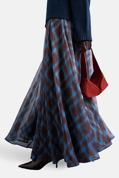 Lange, veelkleurige rok van TOPSHOP, met een geruit patroon en gedragen met een marineblauwe trui en leren laarzen.
