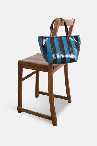 Blauwe schoudertas van TOPSHOP met bruine strepen, hangend aan een houten stoel.
