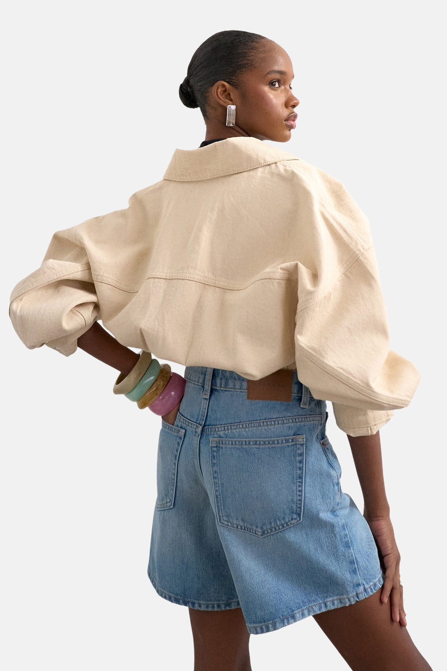 Lichtblauwe denim shorts van TOPSHOP, achterzijde met zakken, model draagt beige overhemd en kleurrijke armbanden