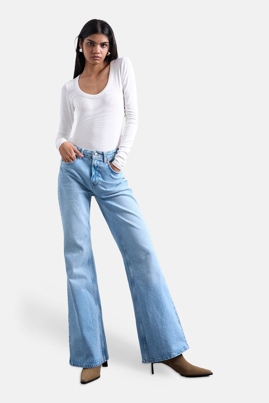 Lichtblauwe denim flared jeans van Topshop, met een bootcut pasvorm en gedragen met een wit shirt en bruine laarzen.