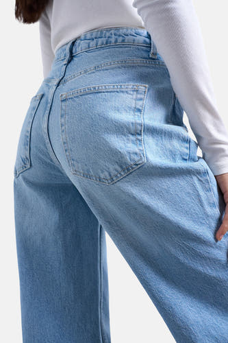 Lichtblauwe denim flared jeans van TOPSHOP, achterkant gezien, met steekzakken en een wit geribd shirt.