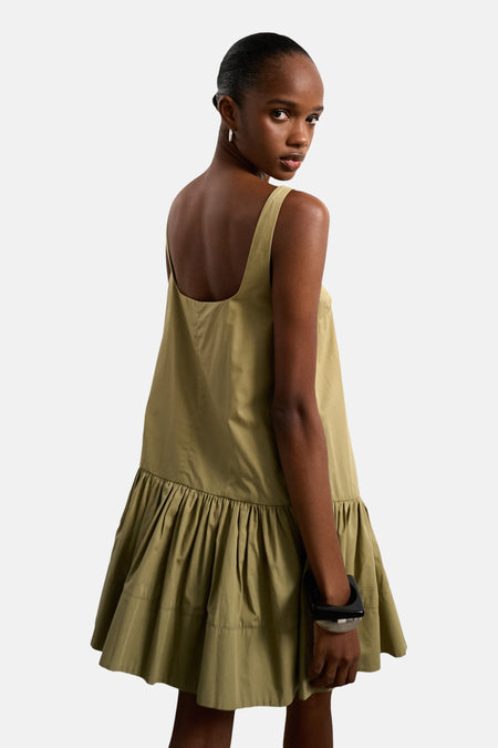 Mouwloze groene kleedje van TOPSHOP, met een geplooide zoom en een model dat over de schouder kijkt.
