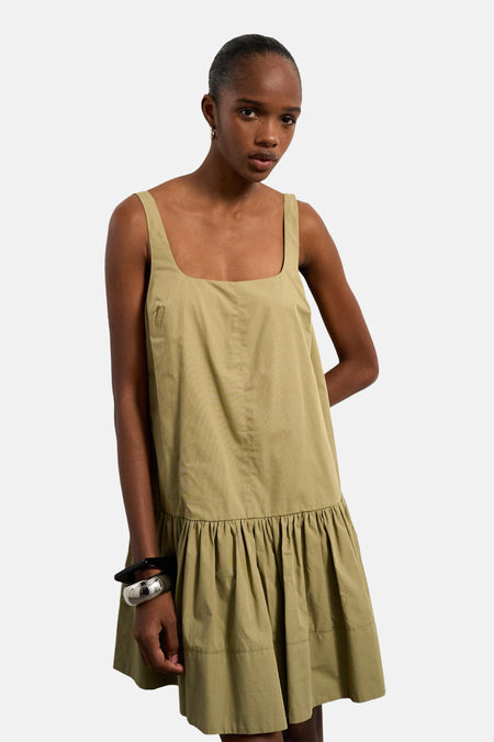 Groene kleedje zonder mouwen van TOPSHOP, met een rechte halslijn en een geplooide rokrand, gecombineerd met zilverkleurige armbanden.
