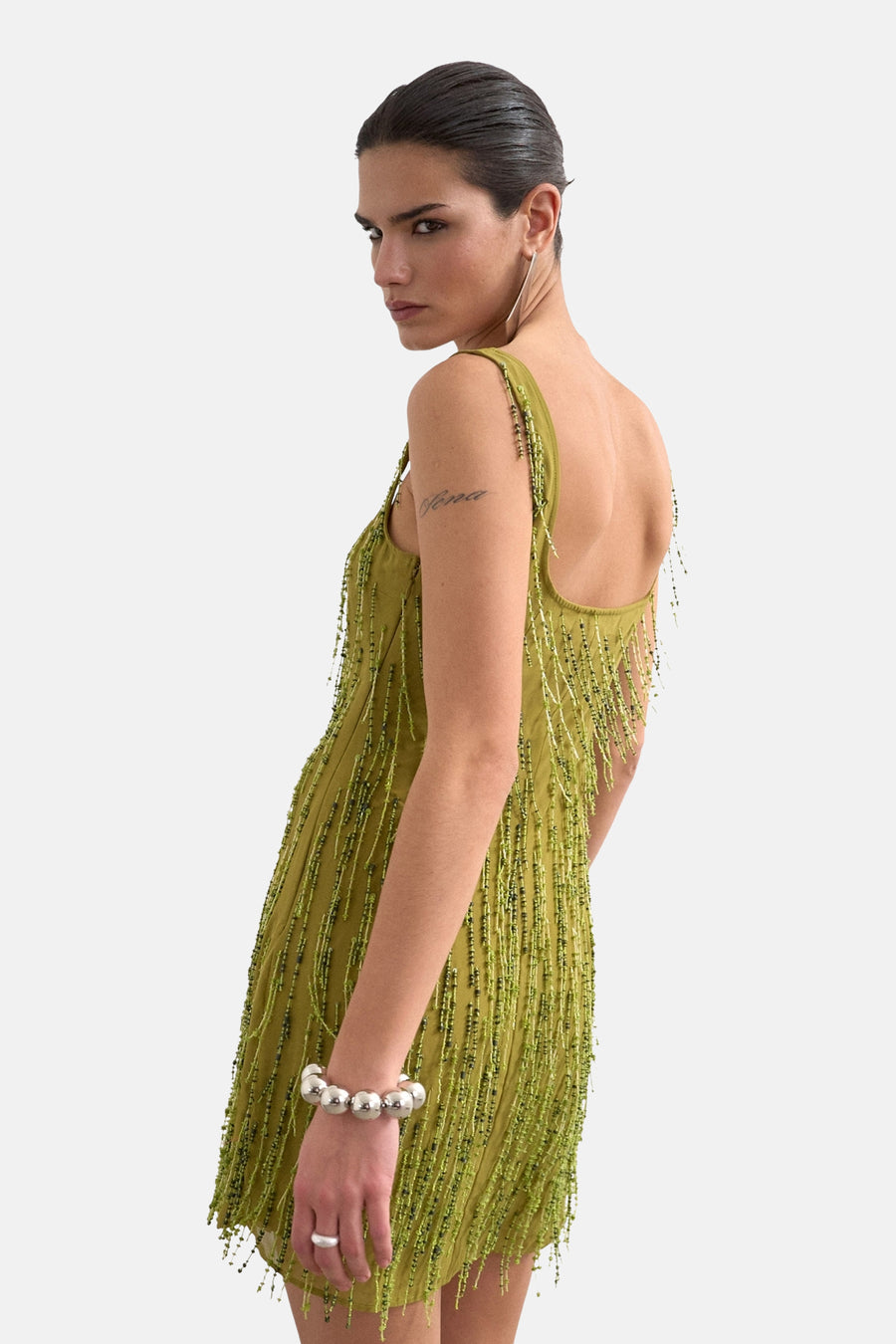 Groene mouwloze kleedje van TOPSHOP, met kralen versierd, gedragen met een zilveren armband en ring.
