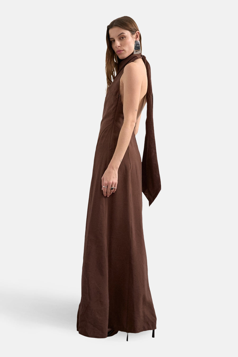 Bruine mouwloze jurk van TOPSHOP, met een open rug en lange sjaal, gedragen met opvallende zilveren oorbellen.