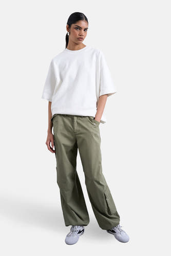 Groene cargobroek van TOPSHOP, met wijde pijpen en zichtbare zakken, gecombineerd met een witte top en grijze sneakers.
