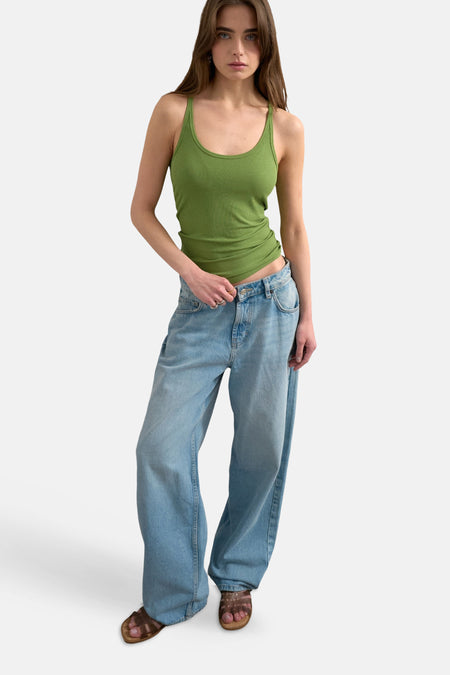 Débardeur vert de TOPSHOP, porté avec un jean oversize et des sandales marron.