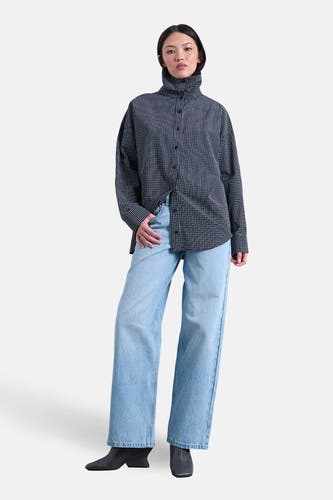 Wijde jeans van lichtblauw denim van TOPSHOP, gecombineerd met een zwart-wit geruit overhemd en zwarte enkellaarsjes.