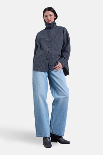 Wijde jeans van lichtblauw denim van TOPSHOP, gecombineerd met een geruite blouse met lange mouwen en zwarte laarzen.