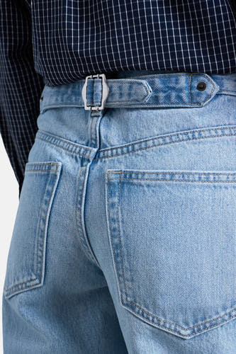 Wijde lichtblauwe denim jeans van TOPSHOP, met riem en zilveren gesp, achterkant zichtbaar.