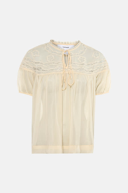 Blouse écru transparente à manches courtes de TOPSHOP, avec détails en dentelle et fermeture à nouer au col.